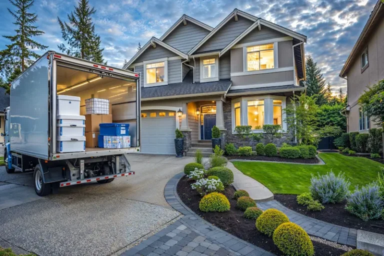 A moving truck parked outside a large suburban home