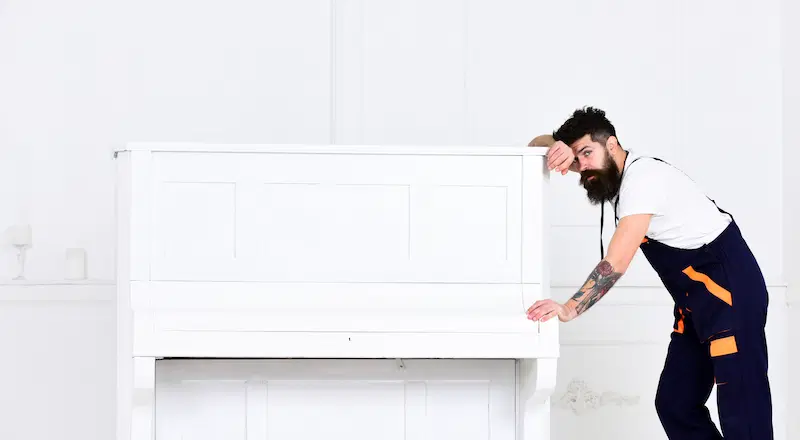 Tired man preparing to carry a heavy piano